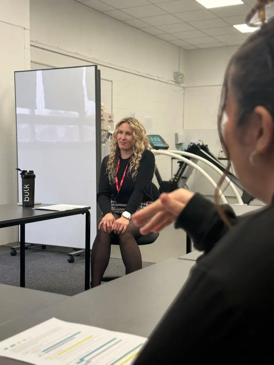 Klaudia watching a learner practise signing during a class